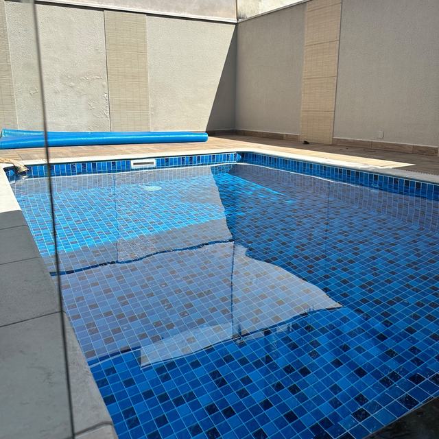 Piscina com revestimento azul em pátio de paredes claras