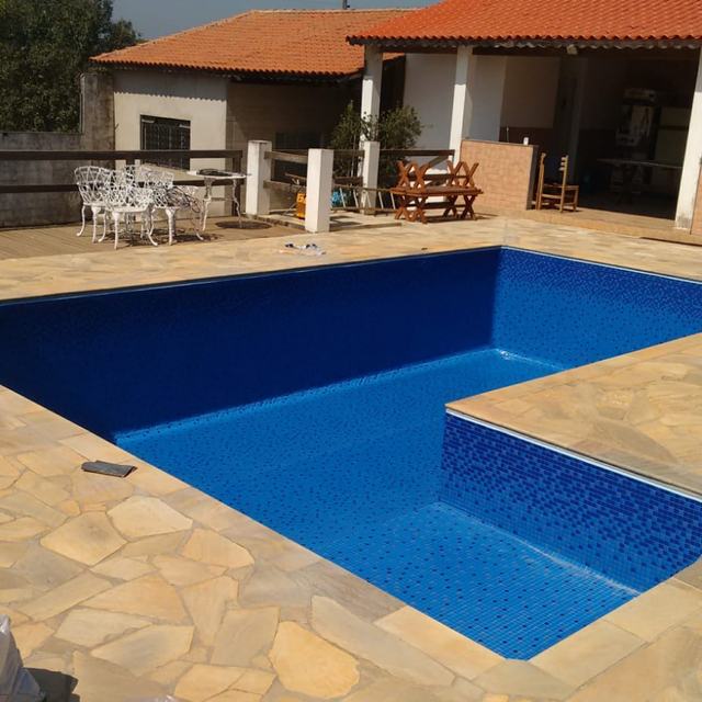 Piscina em L com vinil azul durante a obra, com deck de pedra