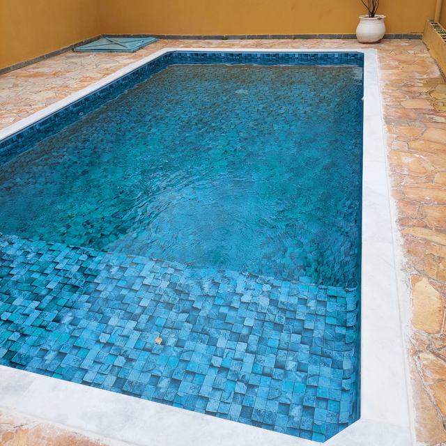 Piscina com revestimento azul-esverdeado, borda clara e parede amarela